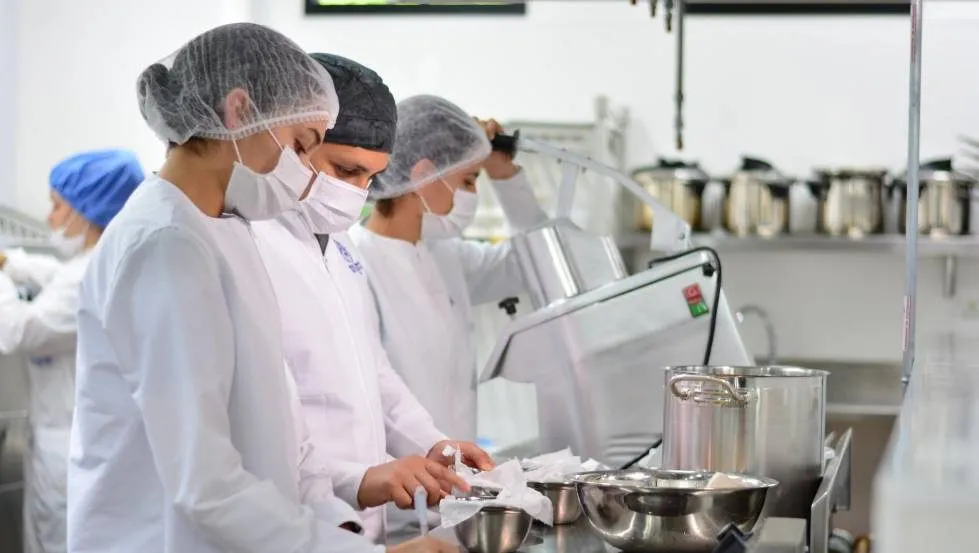 Manipuladoras de alimentos en producción comercio y alérgenos trabajando en cocina industrial