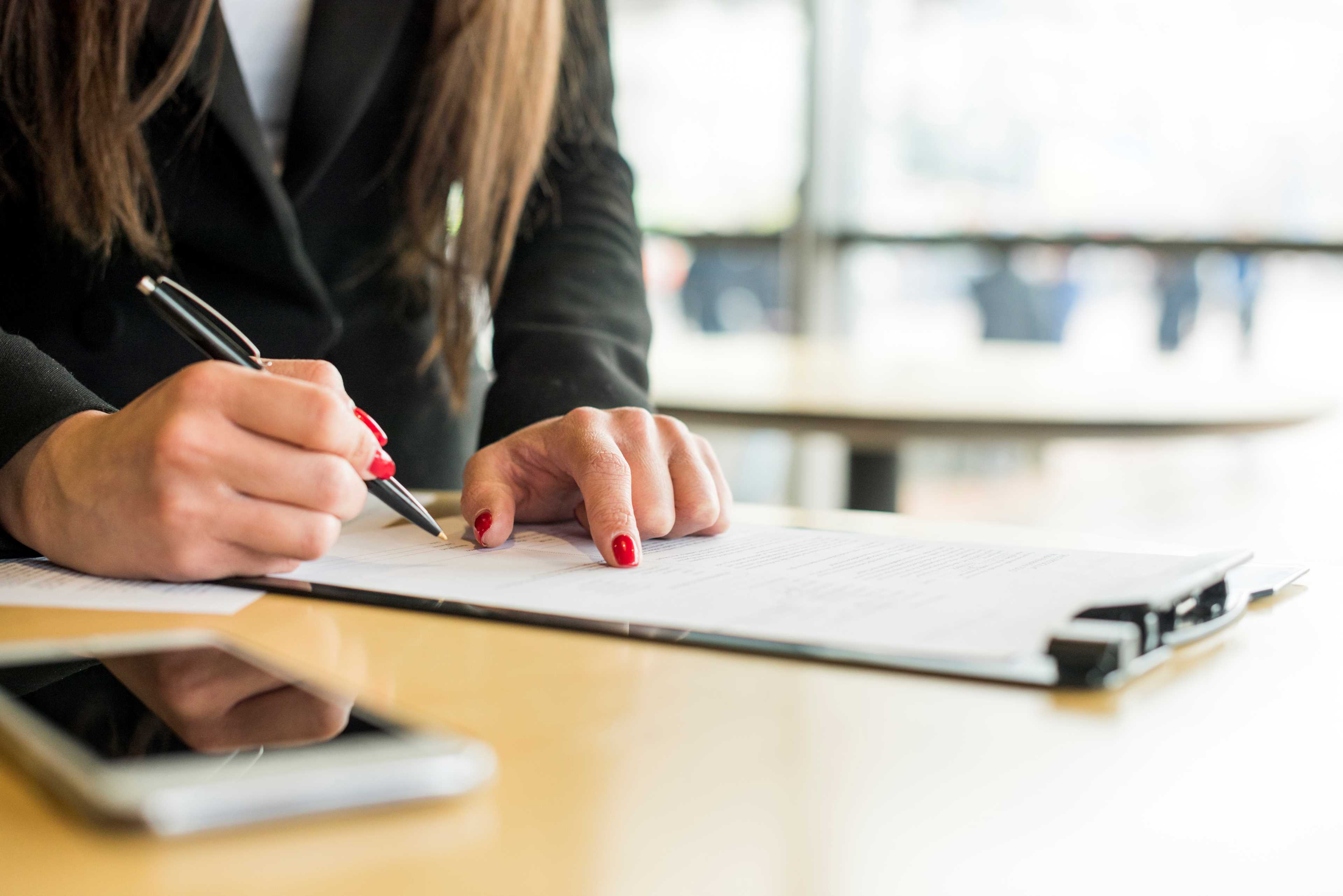 Mano de una mujer sobre un documento realizando firma